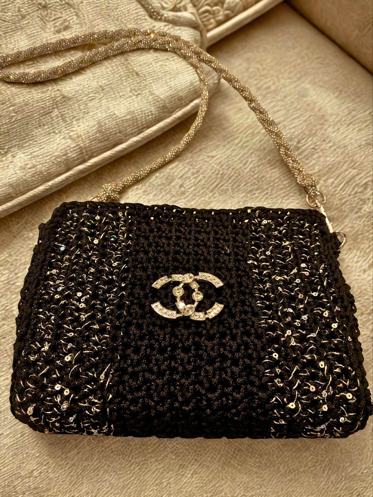 Black beaded handbag with Chanel logo on a beige surface