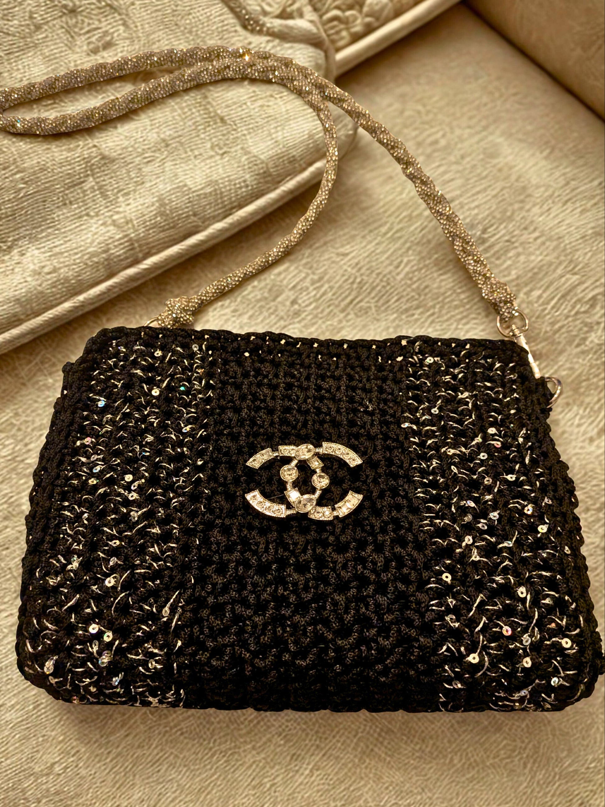 Black beaded handbag with Chanel logo on a beige surface