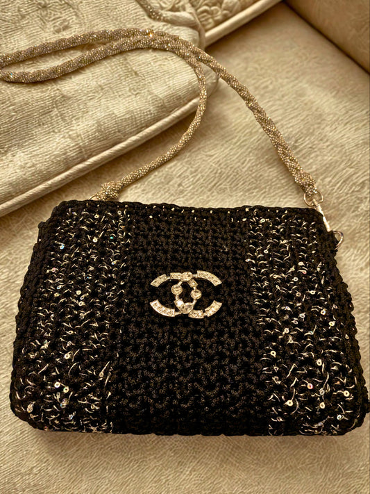 Black beaded handbag with Chanel logo on a beige surface